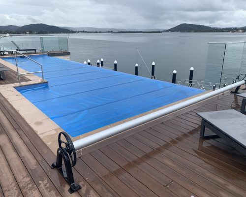 500 Micron Pool Cover on Infinity Edge Pool hooked up to a Black Stationary Powder-Coated Aluminium Roller